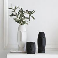 White Nordic ceramic face-art vase holding an olive branch