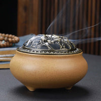 Ceramic Buddha Incense Burner with antique copper lid and smoke, perfect for meditation and calming spaces.