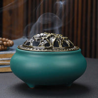 Ceramic Buddha Incense Burner with antique copper lid and smoke, perfect for meditation and calming spaces.