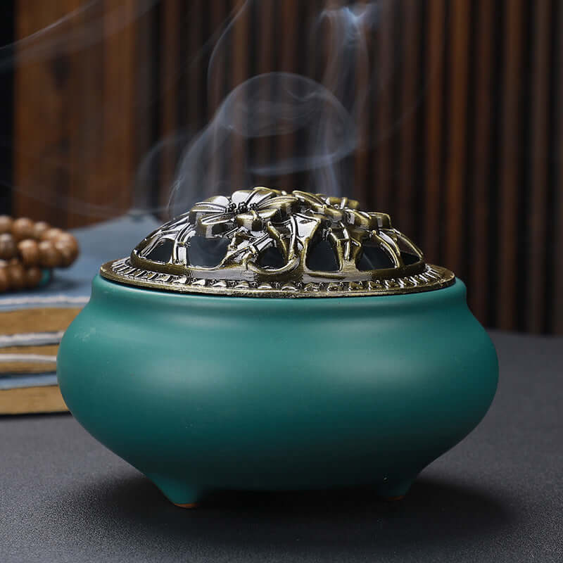 Ceramic Buddha Incense Burner with antique copper lid and smoke, perfect for meditation and calming spaces.