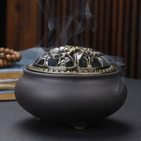 Ceramic Buddha Incense Burner with antique copper lid and smoke, perfect for meditation and calming spaces.
