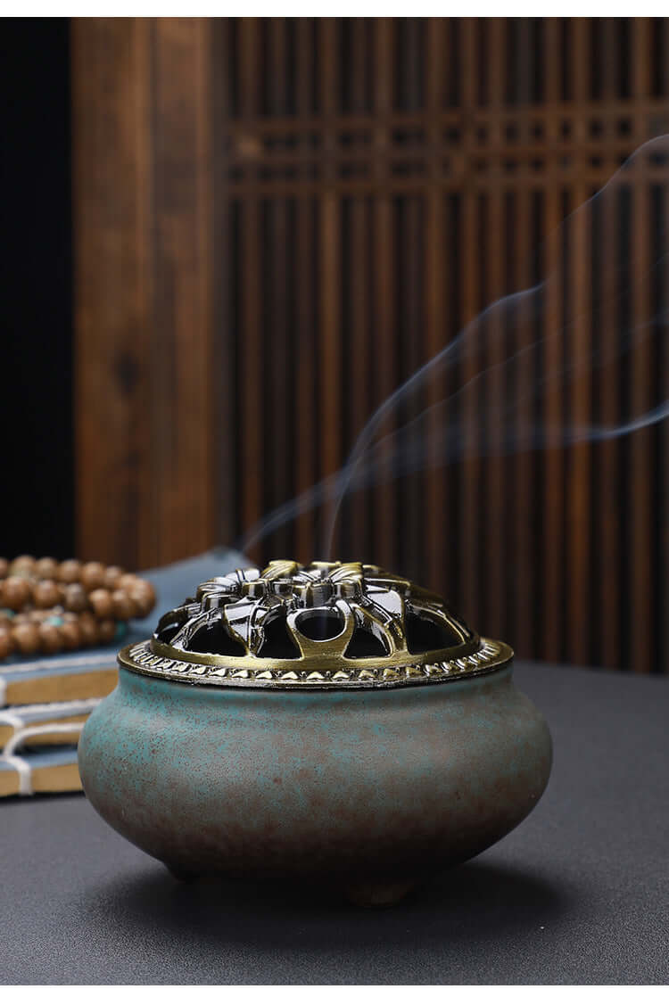 Ceramic Buddha Incense Burner with antique copper lid and smoke, perfect for meditation and calming spaces.