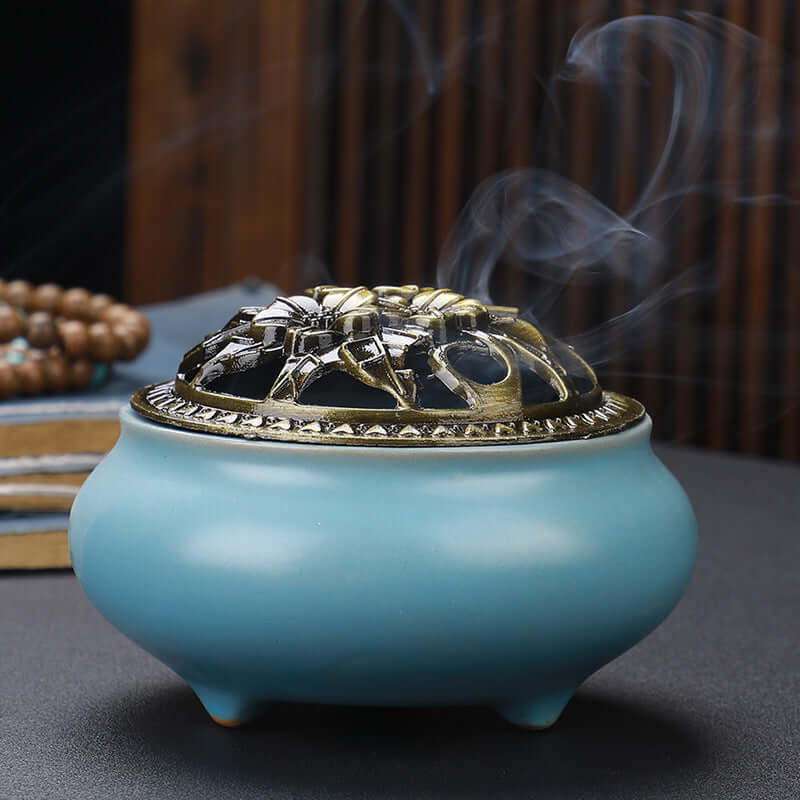 Ceramic Buddha Incense Burner with antique copper lid and smoke, perfect for meditation and calming spaces.