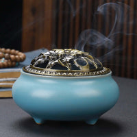 Ceramic Buddha Incense Burner with antique copper lid and smoke, perfect for meditation and calming spaces.