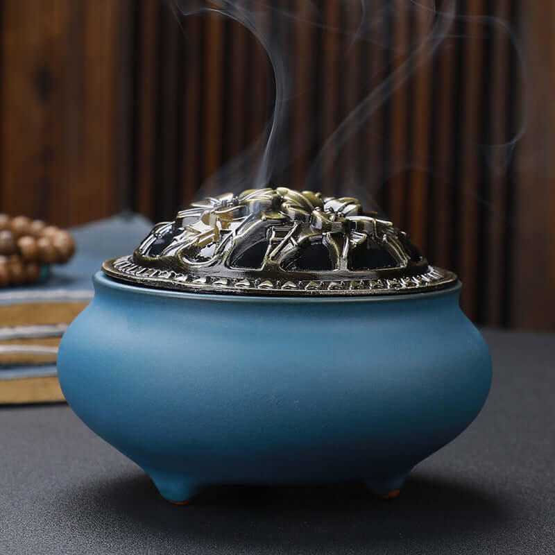 Ceramic Buddha Incense Burner with antique copper lid and smoke, perfect for meditation and calming spaces.