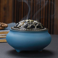 Ceramic Buddha Incense Burner with antique copper lid and smoke, perfect for meditation and calming spaces.