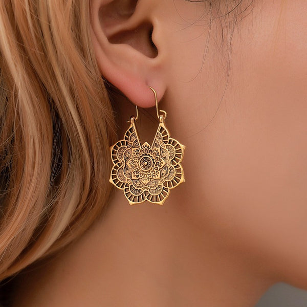 Gold retro mandala floral carved metal dangle earring worn on model's ear