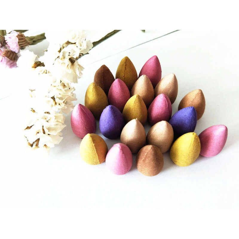 Assortment of multicolored backflow incense cones arranged with dried flowers