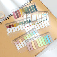 Pastel-colored sticky note index tabs with ruler markings on a spiral notebook