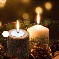 Rustic wooden log tealight candle holder with a lit candle among pine branches and pinecones